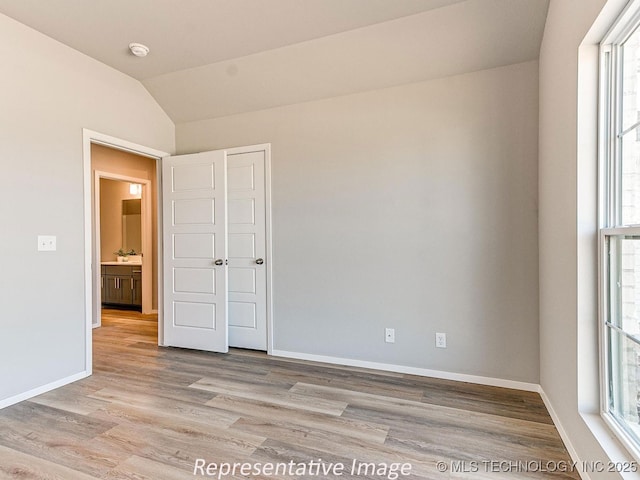 empty room with light hardwood / wood-style flooring and vaulted ceiling