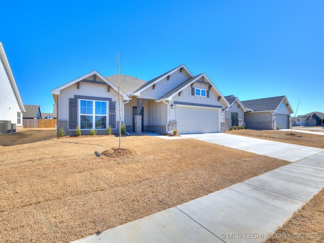 craftsman-style home with board and batten siding, concrete driveway, central AC, stone siding, and an attached garage