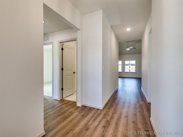 hall featuring visible vents, recessed lighting, baseboards, and wood finished floors