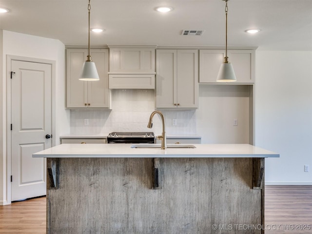 kitchen with light countertops, visible vents, backsplash, and a sink