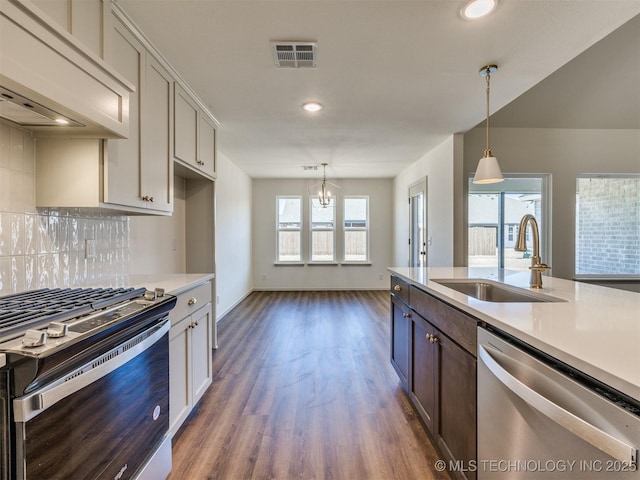 kitchen with visible vents, a sink, tasteful backsplash, stainless steel appliances, and light countertops