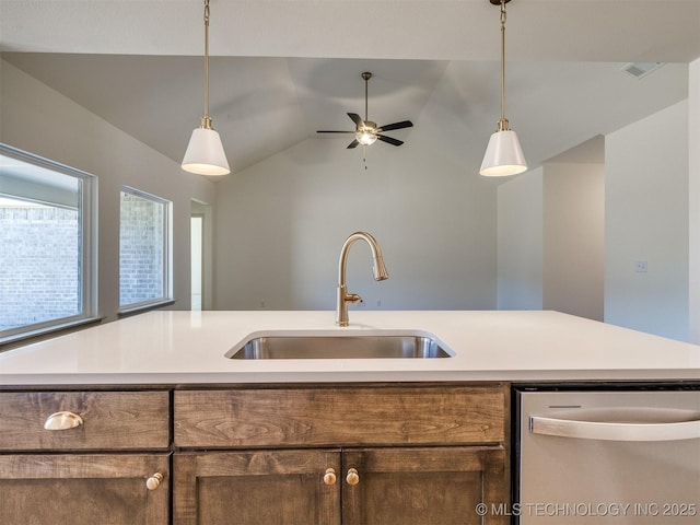 kitchen featuring a sink, stainless steel dishwasher, light countertops, and hanging light fixtures