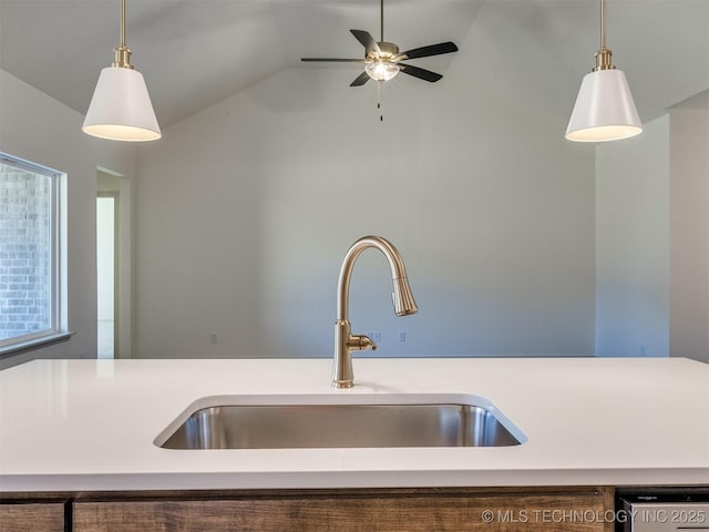 kitchen with lofted ceiling, decorative light fixtures, light countertops, and a sink