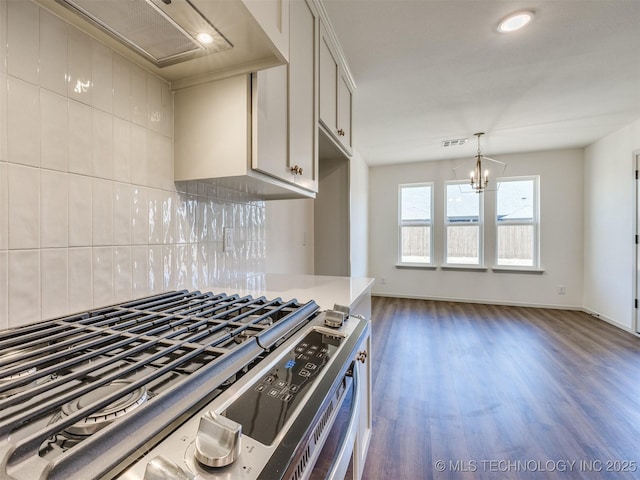 kitchen featuring backsplash, premium range hood, wood finished floors, a notable chandelier, and stainless steel gas range