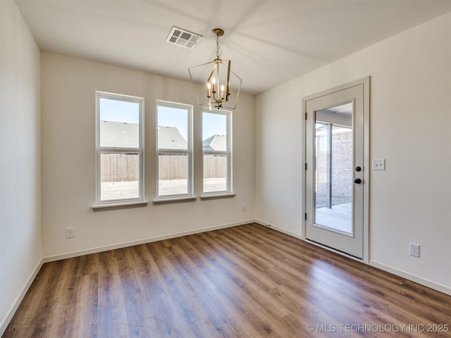 unfurnished dining area with a notable chandelier, visible vents, baseboards, and wood finished floors