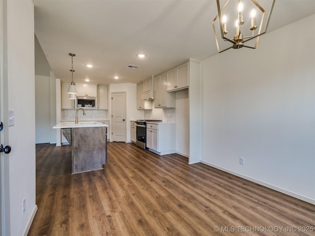 kitchen with stainless steel microwave, range with gas cooktop, dark wood finished floors, decorative backsplash, and a sink