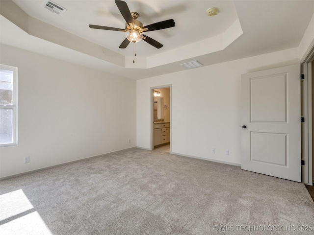 unfurnished bedroom featuring visible vents, baseboards, and a tray ceiling