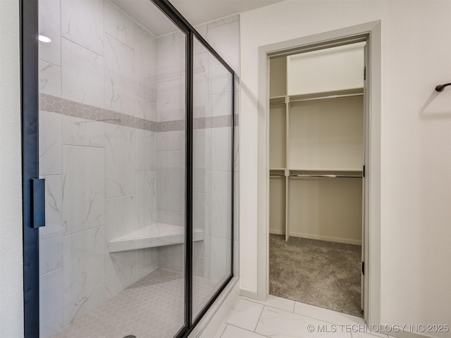 bathroom with a spacious closet, baseboards, a stall shower, and marble finish floor