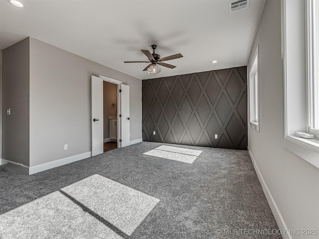 spare room featuring ceiling fan and dark carpet