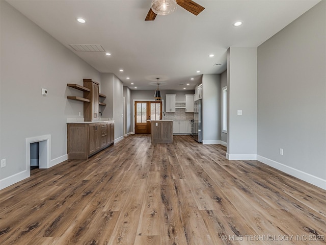 unfurnished living room with ceiling fan and light wood-type flooring