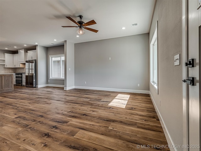 unfurnished living room featuring dark wood-type flooring and ceiling fan