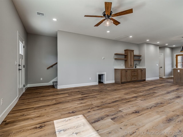 unfurnished living room with sink, hardwood / wood-style flooring, and ceiling fan