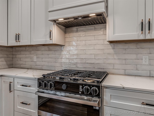 kitchen with custom exhaust hood, stainless steel gas range oven, tasteful backsplash, and white cabinets