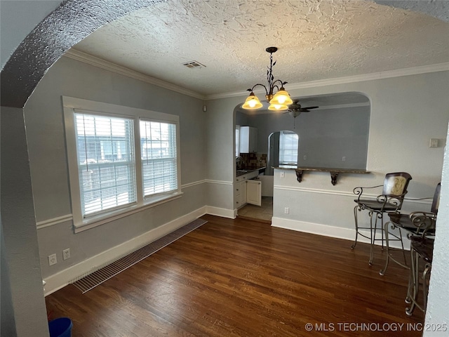 dining area featuring sink, dark hardwood / wood-style floors, a textured ceiling, ceiling fan with notable chandelier, and ornamental molding