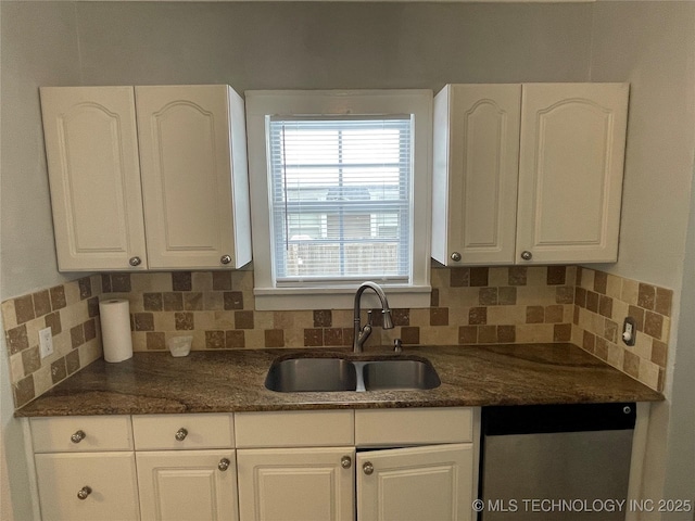 kitchen with decorative backsplash, white cabinetry, dark stone countertops, and sink