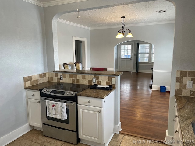 kitchen with a textured ceiling, stainless steel electric range oven, pendant lighting, a notable chandelier, and white cabinetry