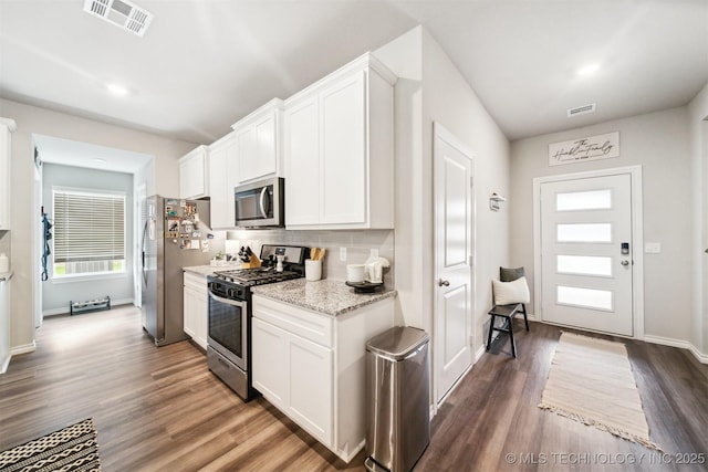 kitchen featuring light stone countertops, appliances with stainless steel finishes, dark hardwood / wood-style flooring, and white cabinetry