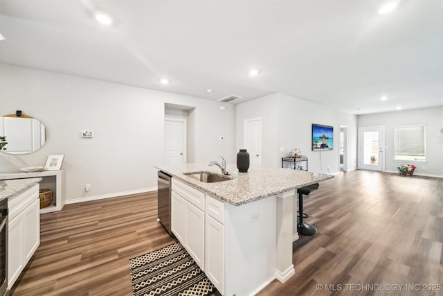 kitchen featuring light stone counters, sink, a center island with sink, dishwasher, and white cabinetry