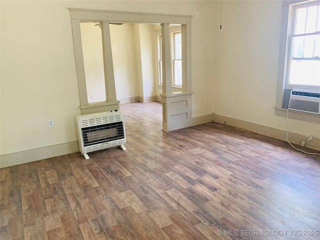 unfurnished living room with light wood-type flooring, heating unit, ornate columns, and cooling unit