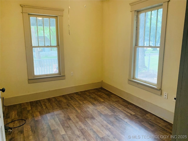 unfurnished room featuring plenty of natural light and dark wood-type flooring