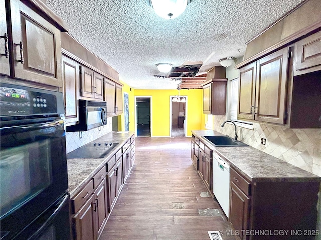 kitchen featuring black appliances, sink, dark hardwood / wood-style floors, a textured ceiling, and tasteful backsplash