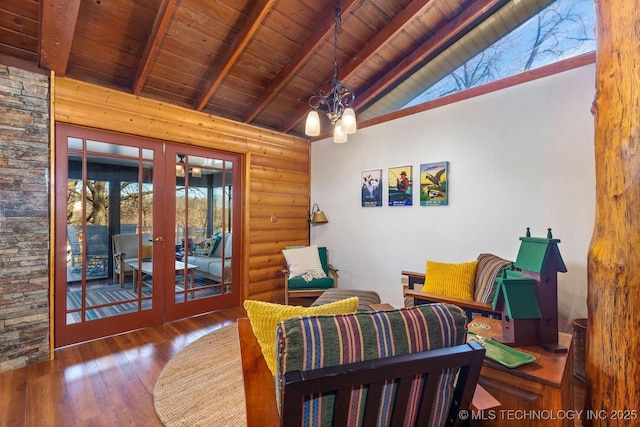 sitting room with beam ceiling, rustic walls, french doors, an inviting chandelier, and wood ceiling