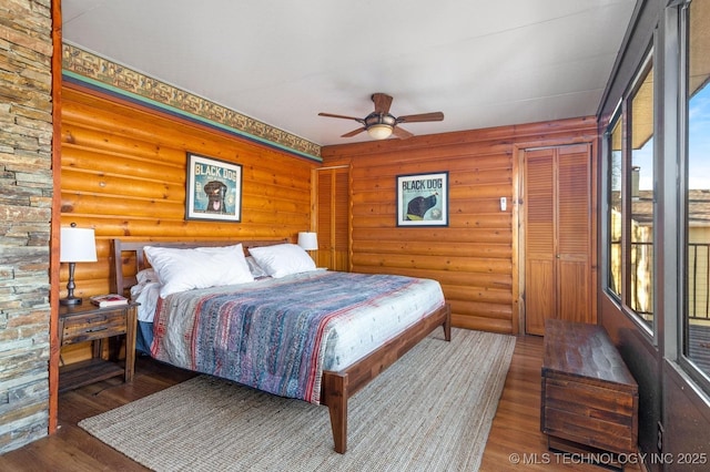 bedroom with ceiling fan, dark wood-type flooring, and log walls