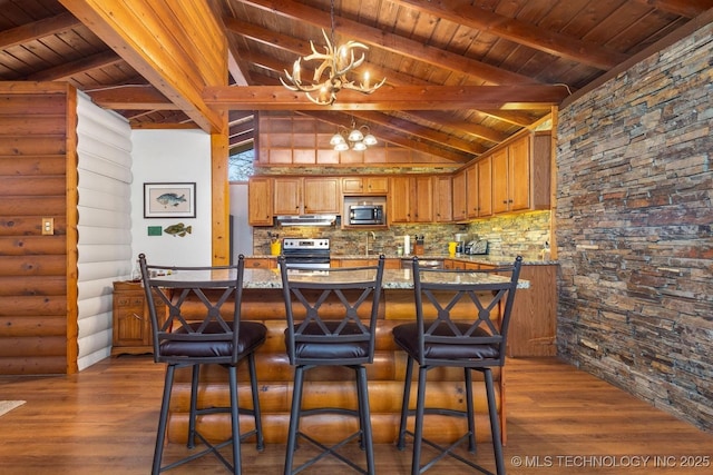 kitchen with dark wood-type flooring, log walls, a chandelier, and appliances with stainless steel finishes