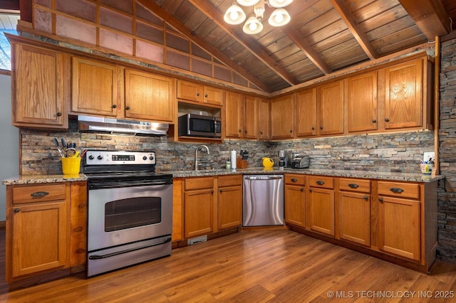 kitchen with sink, stainless steel appliances, wooden ceiling, vaulted ceiling with beams, and light stone counters