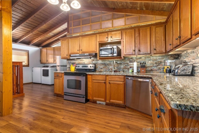 kitchen featuring sink, vaulted ceiling with beams, washer and dryer, appliances with stainless steel finishes, and wood-type flooring