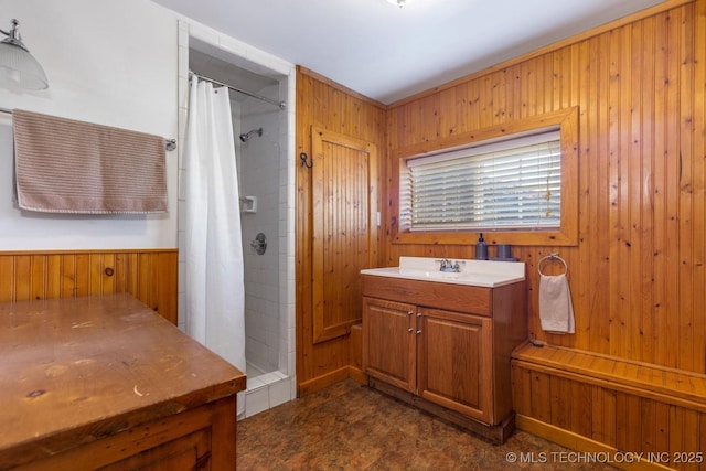 bathroom featuring curtained shower, wood walls, and vanity