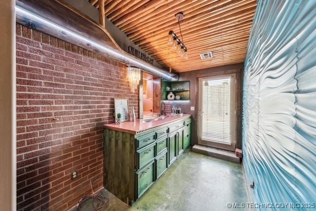 bar featuring concrete flooring, sink, brick wall, and green cabinetry