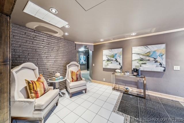 sitting room featuring light tile patterned floors, ornamental molding, and brick wall