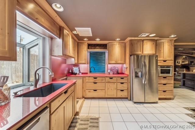 kitchen featuring sink, light tile patterned floors, light brown cabinets, and appliances with stainless steel finishes