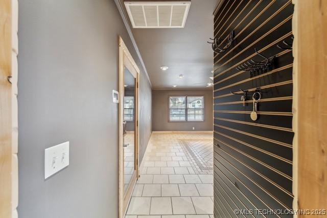 hall featuring crown molding and light tile patterned floors