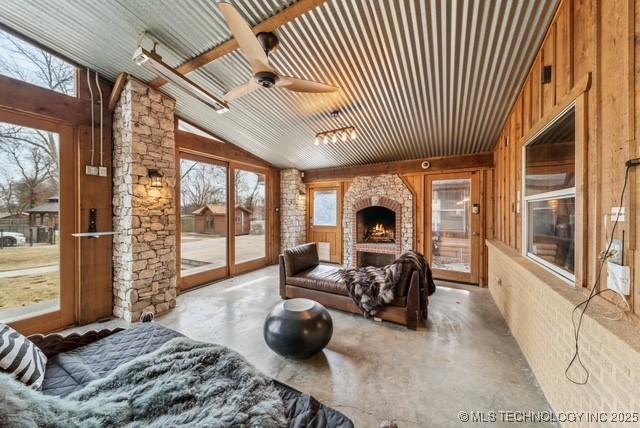 sunroom featuring ceiling fan, a large fireplace, and lofted ceiling