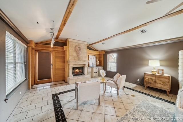 living room with lofted ceiling with beams, light tile patterned floors, and a fireplace