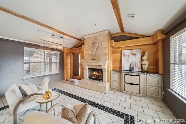 living room with lofted ceiling with beams, a healthy amount of sunlight, and a tiled fireplace