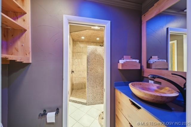 bathroom with tiled shower, vanity, tile patterned flooring, and ornamental molding