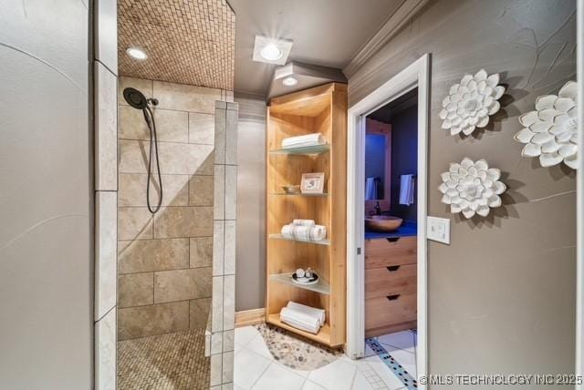 bathroom with tile patterned flooring, built in shelves, a tile shower, and ornamental molding