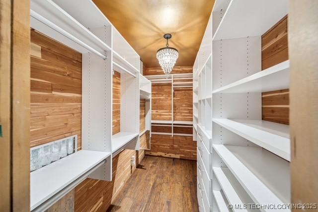 spacious closet featuring hardwood / wood-style flooring and a notable chandelier