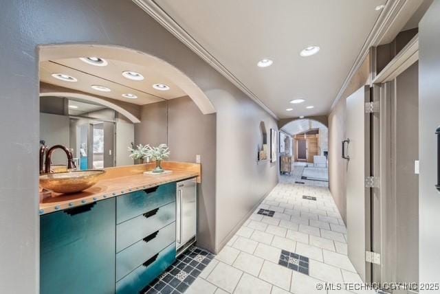 hall with tile patterned floors, ornamental molding, and sink