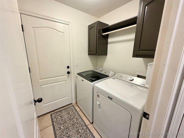 clothes washing area featuring light tile patterned floors, separate washer and dryer, and cabinet space