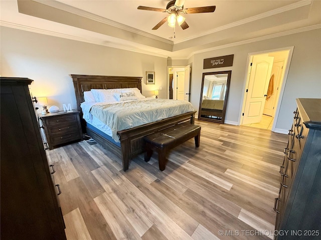 bedroom with a ceiling fan, baseboards, ornamental molding, light wood finished floors, and a raised ceiling