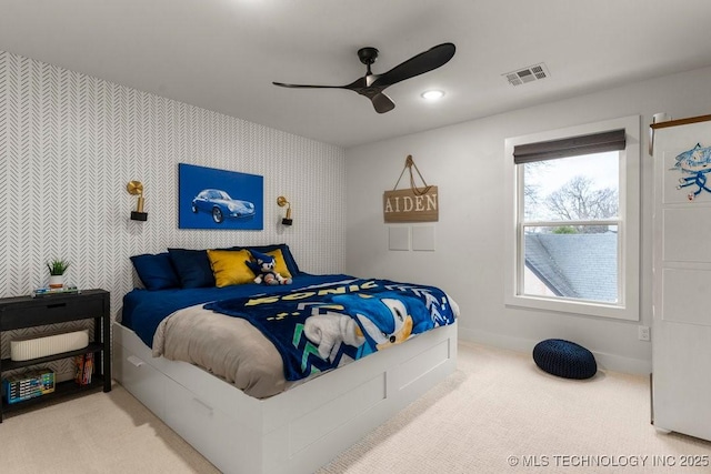 carpeted bedroom with baseboards, wallpapered walls, a ceiling fan, an accent wall, and visible vents