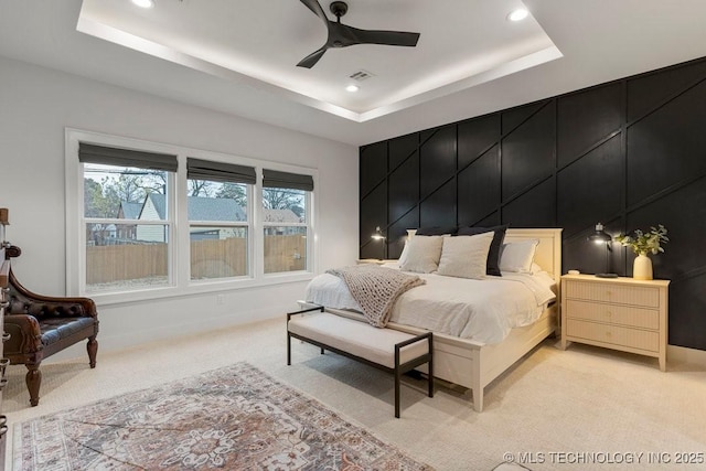 bedroom with a tray ceiling, ceiling fan, and light colored carpet