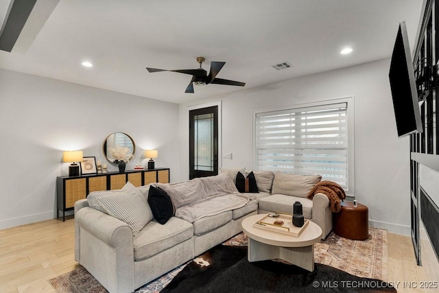 living area with light wood finished floors, visible vents, baseboards, and a ceiling fan