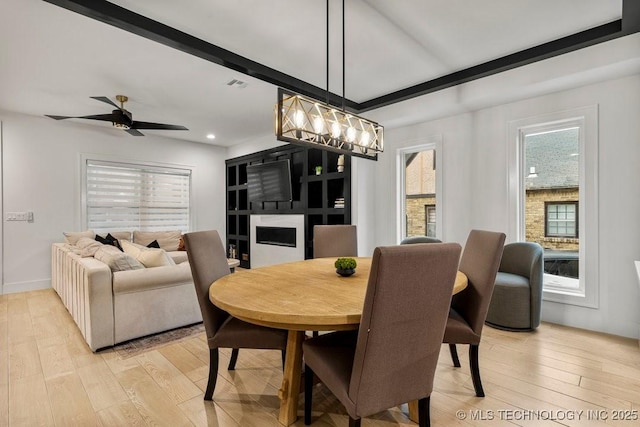 dining space with ceiling fan with notable chandelier and light hardwood / wood-style flooring