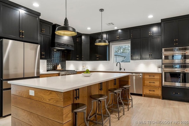 kitchen featuring dark cabinets, visible vents, light wood-style flooring, and stainless steel appliances