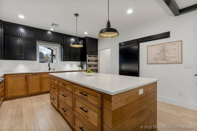 kitchen with sink, a center island, light hardwood / wood-style flooring, backsplash, and pendant lighting